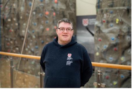 Richard Collis standing in front of a climbing wall